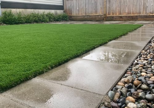 Low maintenance backyard installation of artificial lawn, concrete pavers, and river rock