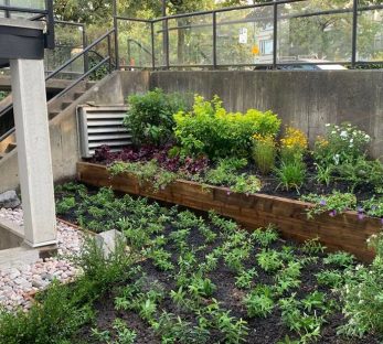 Installation of condo garden space including: retaining wall, raised garden beds, planting, and small and medium decorative river rock